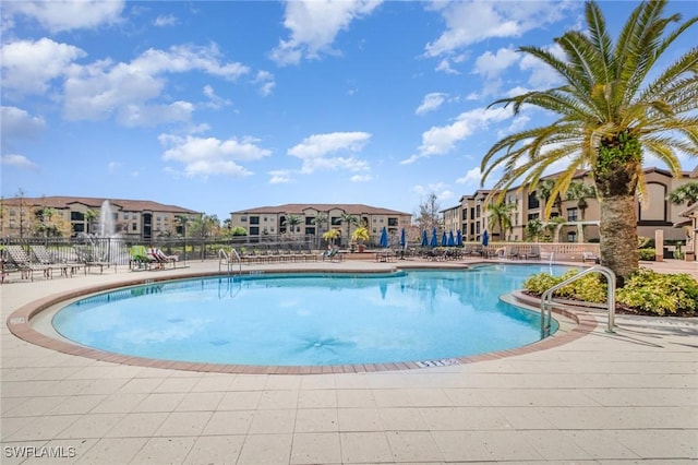 pool with a patio area, a residential view, and fence