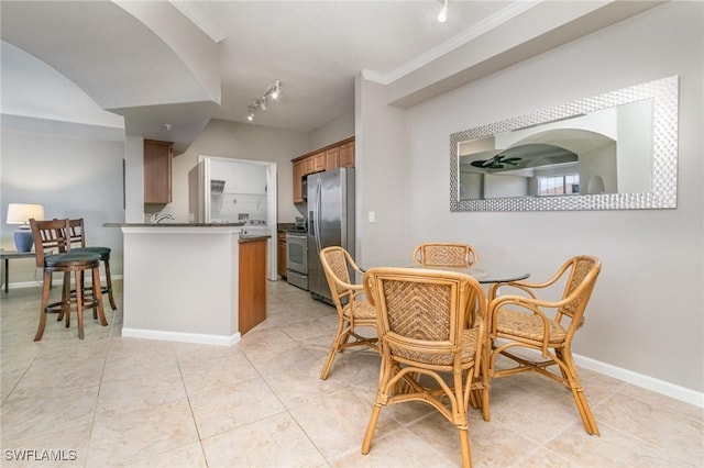 dining room with rail lighting, light tile patterned floors, baseboards, and crown molding