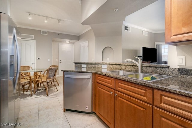 kitchen featuring dark stone counters, appliances with stainless steel finishes, a sink, and visible vents