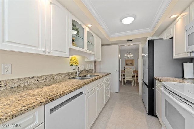 kitchen with white cabinetry, white appliances, light stone countertops, and sink