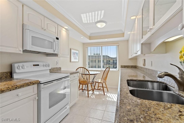 kitchen with white appliances, a raised ceiling, and white cabinets