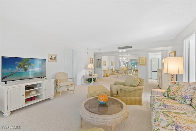 carpeted living room featuring an inviting chandelier