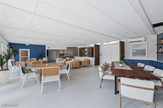 dining space featuring a paneled ceiling and a wall mounted air conditioner