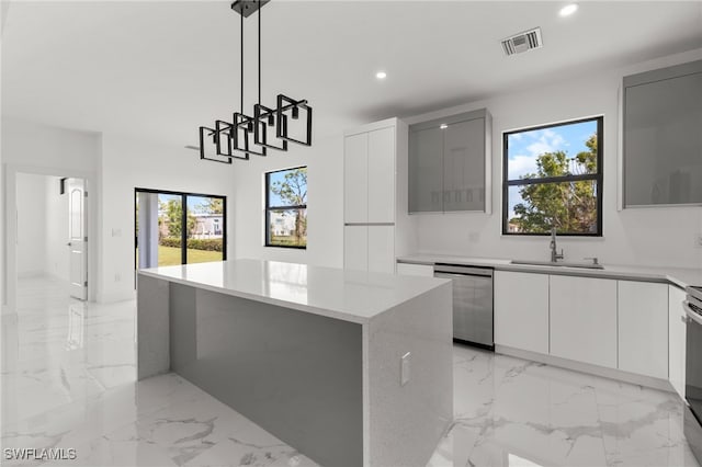 kitchen featuring a kitchen island, appliances with stainless steel finishes, decorative light fixtures, white cabinetry, and sink