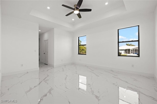 spare room with ceiling fan and a tray ceiling