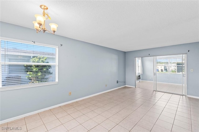 spare room featuring light tile patterned floors, a textured ceiling, and a chandelier