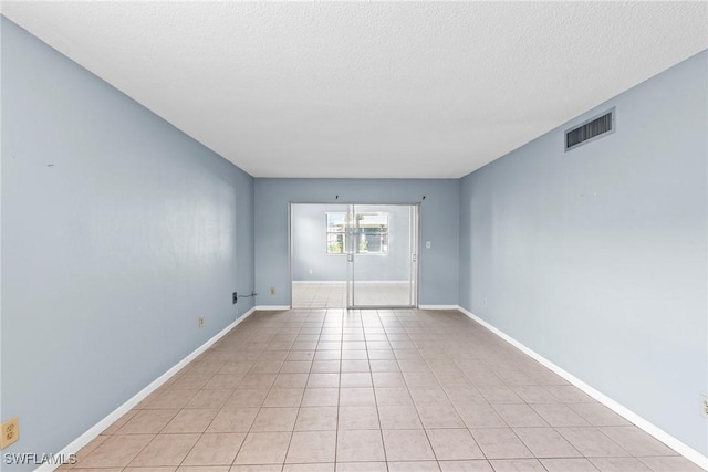 tiled empty room with a textured ceiling