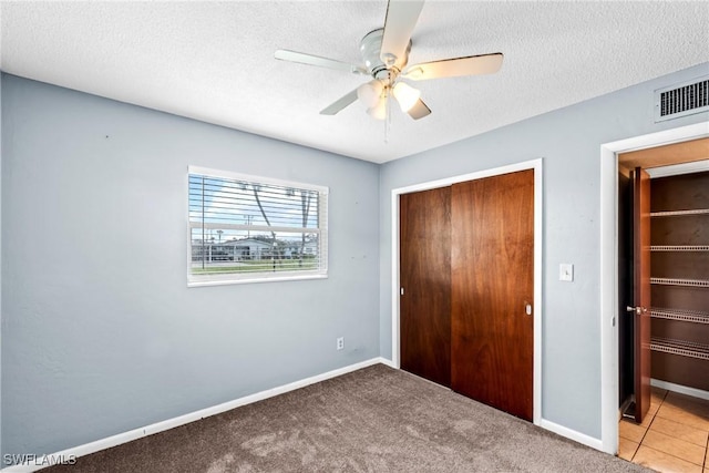 unfurnished bedroom with ceiling fan, carpet, a textured ceiling, and a closet