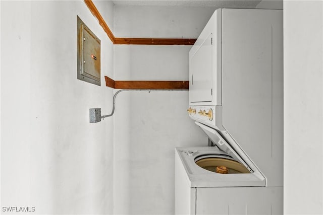 clothes washing area with stacked washer and clothes dryer and electric panel