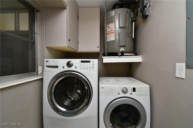 washroom featuring cabinets, water heater, and washing machine and clothes dryer