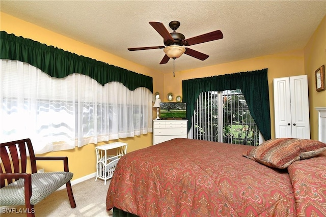 bedroom with ceiling fan, carpet floors, and a textured ceiling