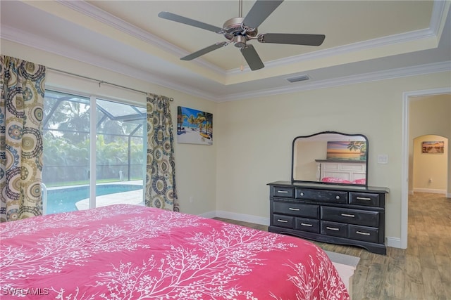 bedroom featuring hardwood / wood-style flooring, ornamental molding, access to outside, ceiling fan, and a tray ceiling