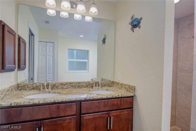 bathroom with tiled shower and vanity