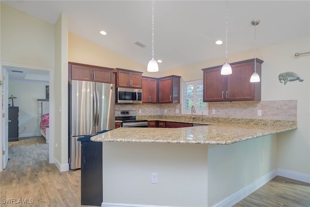 kitchen featuring pendant lighting, appliances with stainless steel finishes, light hardwood / wood-style floors, vaulted ceiling, and kitchen peninsula