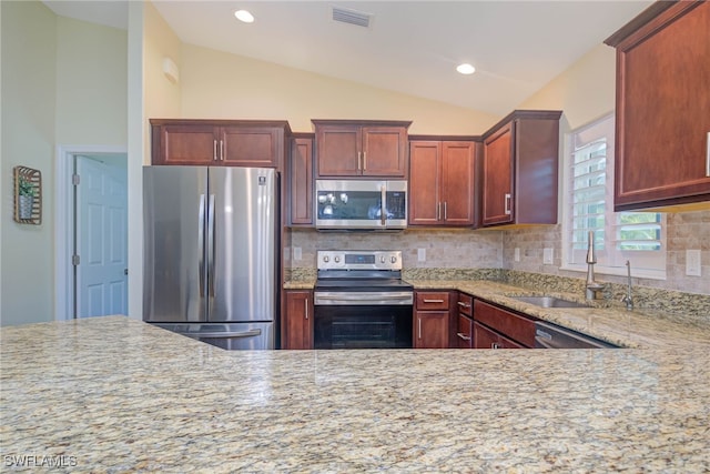 kitchen with vaulted ceiling, sink, backsplash, light stone counters, and stainless steel appliances