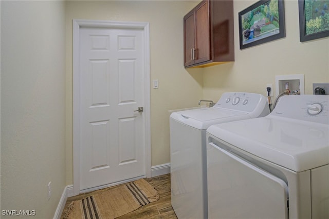 clothes washing area with cabinets, washing machine and dryer, and hardwood / wood-style floors