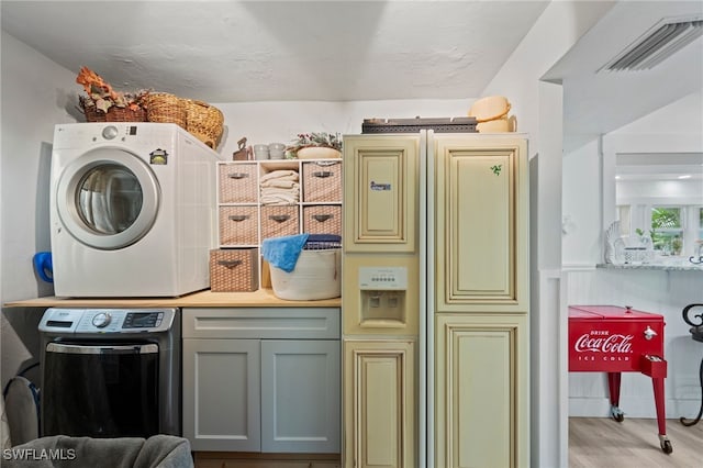 laundry area featuring stacked washer and dryer, cabinets, and light hardwood / wood-style floors