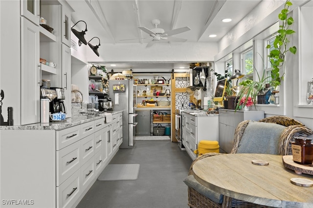 kitchen featuring stainless steel appliances, white cabinetry, light stone countertops, and ceiling fan