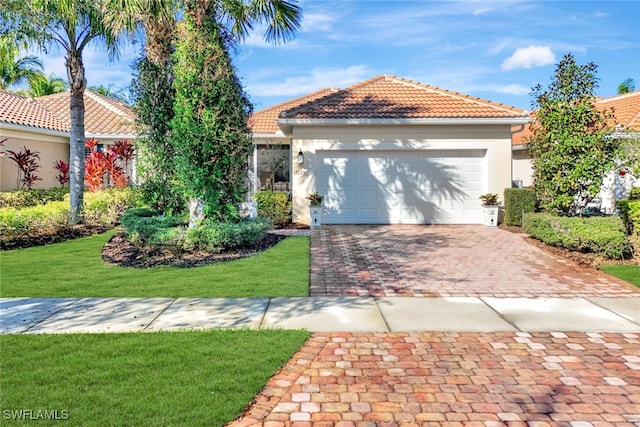 mediterranean / spanish house featuring stucco siding, a front yard, decorative driveway, and a tiled roof