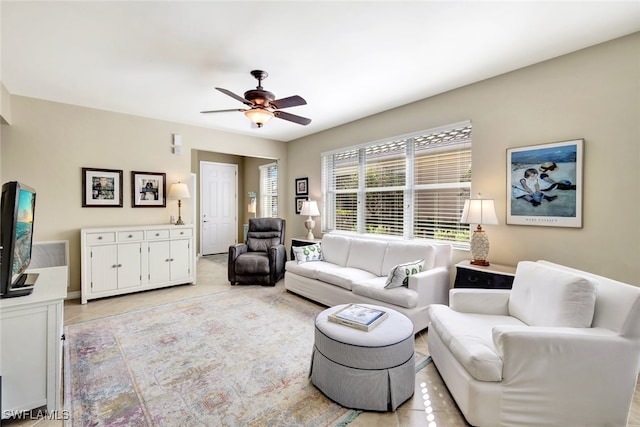 living area with a ceiling fan and light tile patterned floors