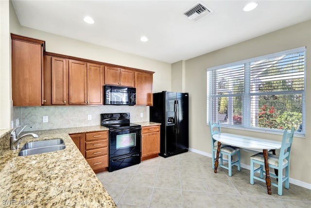 kitchen with light stone counters, visible vents, decorative backsplash, a sink, and black appliances