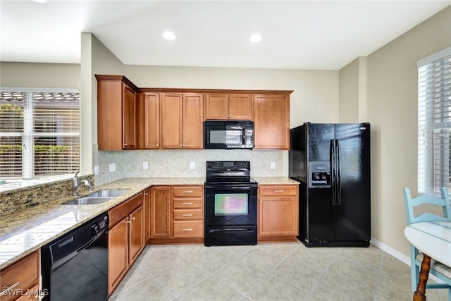 kitchen featuring sink, tasteful backsplash, light tile patterned floors, light stone countertops, and black appliances