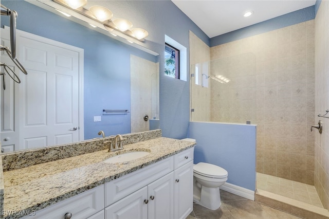 bathroom with vanity, tile patterned floors, toilet, and tiled shower