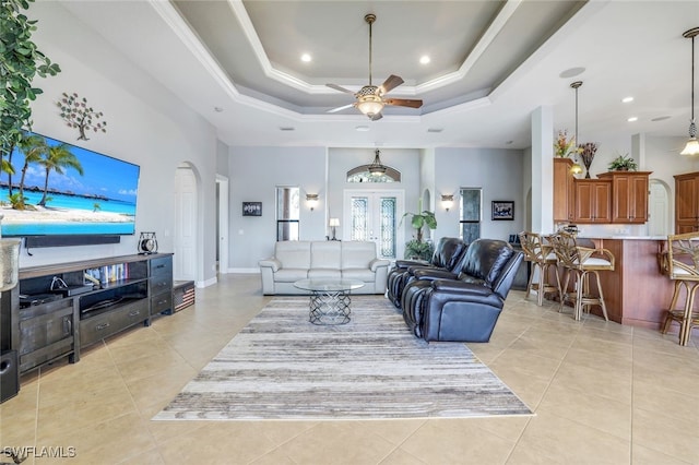 tiled living room with french doors, ornamental molding, a raised ceiling, a towering ceiling, and ceiling fan