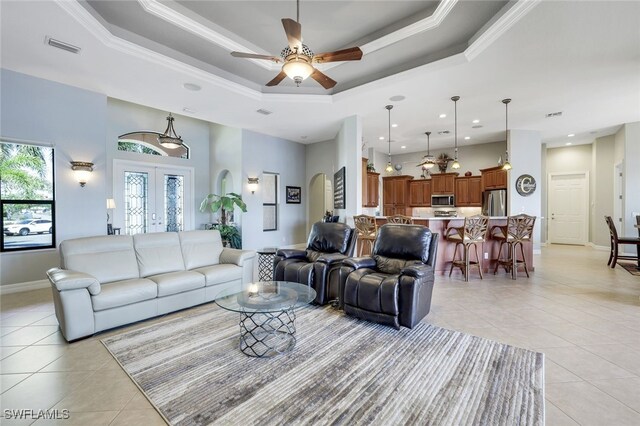 living room with light tile patterned floors, a raised ceiling, and french doors