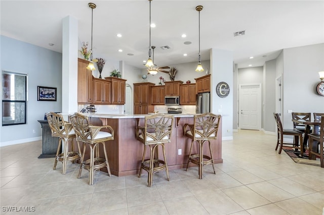 kitchen featuring light tile patterned flooring, a breakfast bar, pendant lighting, kitchen peninsula, and stainless steel appliances