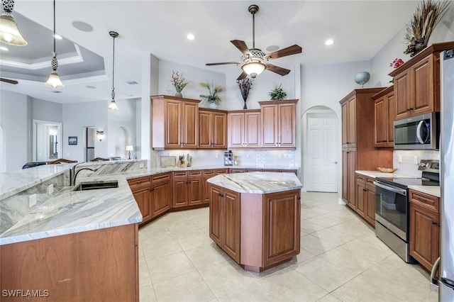 kitchen featuring a kitchen island, appliances with stainless steel finishes, decorative light fixtures, sink, and kitchen peninsula