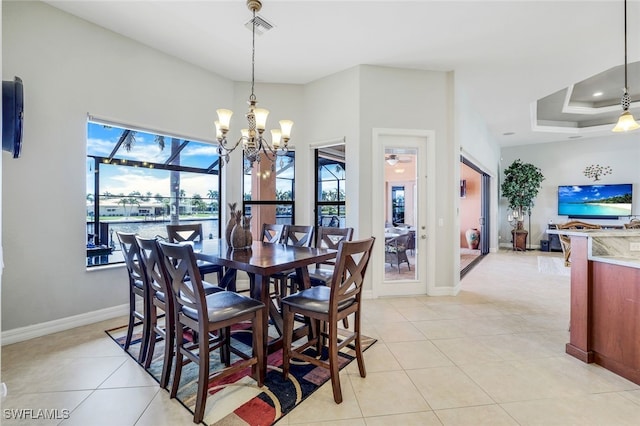 dining room with a notable chandelier, a tray ceiling, and light tile patterned floors