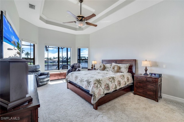 bedroom featuring ceiling fan, a raised ceiling, light carpet, and a towering ceiling