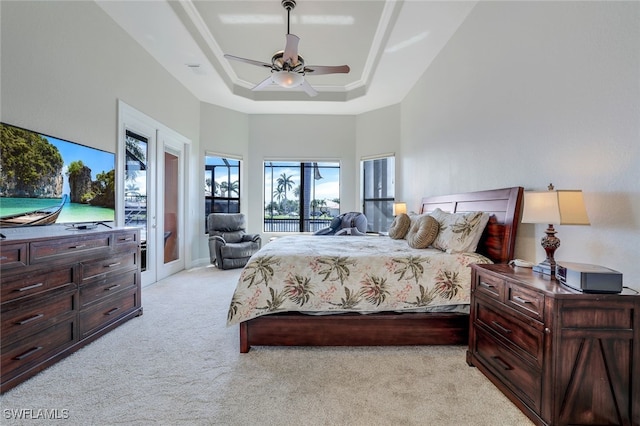 bedroom featuring light carpet, a raised ceiling, ceiling fan, access to exterior, and a high ceiling