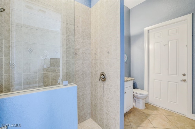 bathroom featuring vanity, tile patterned flooring, toilet, and tiled shower