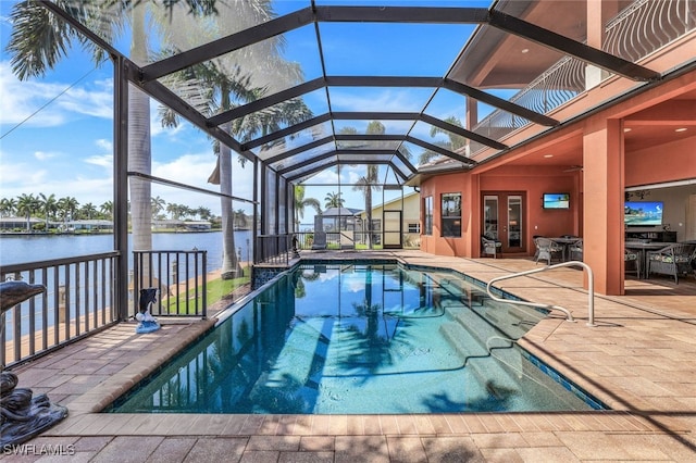 view of swimming pool with a lanai, ceiling fan, a water view, a patio area, and french doors