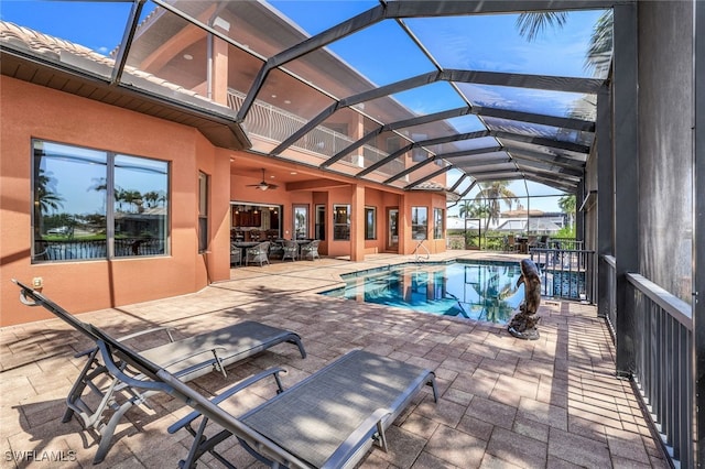 view of swimming pool with a patio area, ceiling fan, and glass enclosure