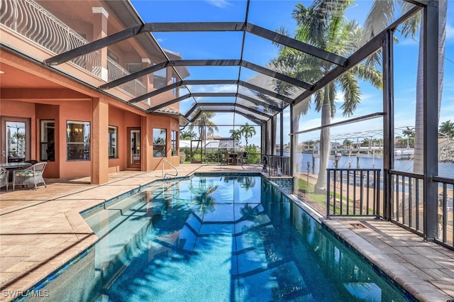 view of pool with a patio, glass enclosure, and a water view