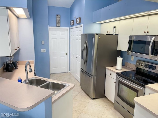 kitchen with sink, white cabinetry, light tile patterned floors, appliances with stainless steel finishes, and kitchen peninsula