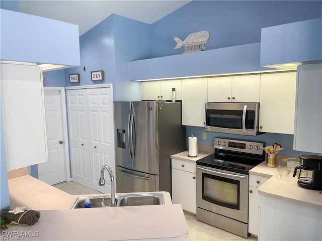 kitchen featuring sink, light tile patterned flooring, white cabinets, and appliances with stainless steel finishes