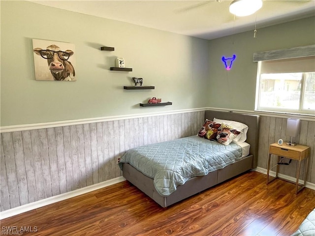 bedroom with wooden walls and dark hardwood / wood-style flooring