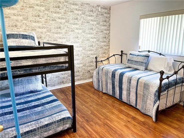 bedroom with hardwood / wood-style flooring and brick wall