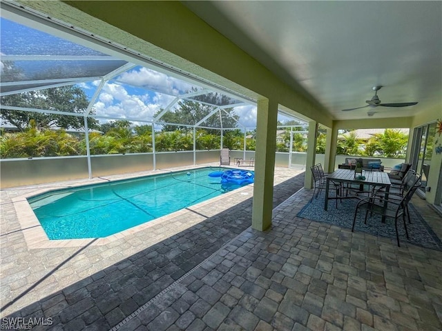 view of swimming pool with ceiling fan, a lanai, and a patio area