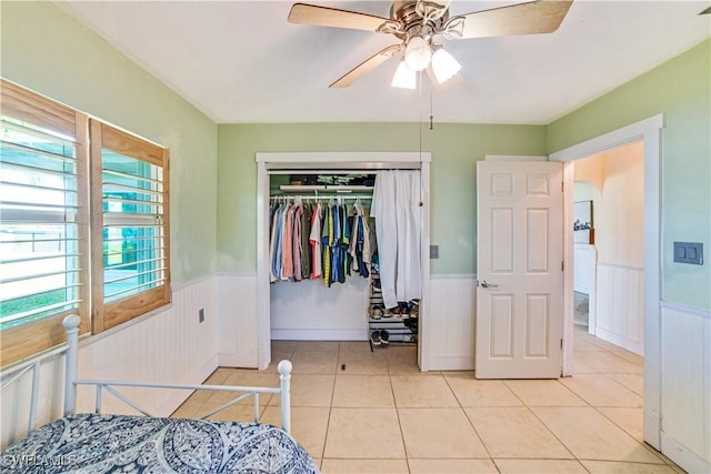 bedroom featuring light tile patterned flooring, ceiling fan, and a closet