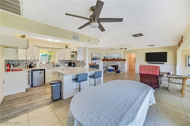 dining space with sink, light tile patterned floors, a fireplace, and ceiling fan