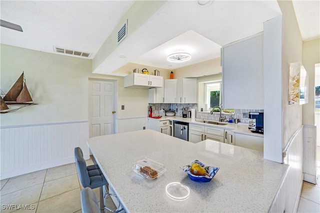 kitchen with dishwasher, sink, a breakfast bar area, white cabinets, and kitchen peninsula