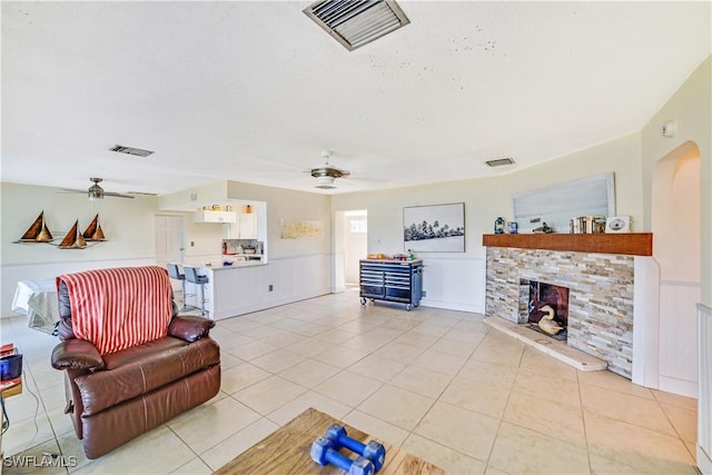 tiled living room with ceiling fan and a fireplace