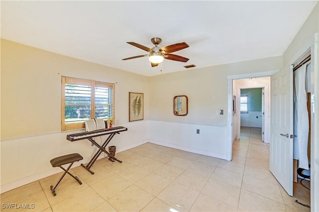 empty room with light tile patterned floors, a wealth of natural light, and ceiling fan