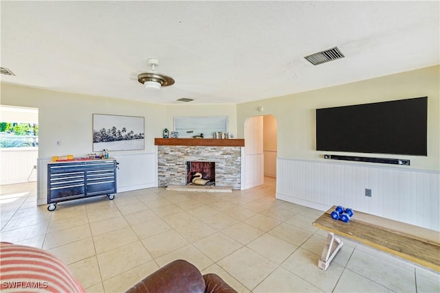 living room with light tile patterned flooring, a stone fireplace, and a textured ceiling