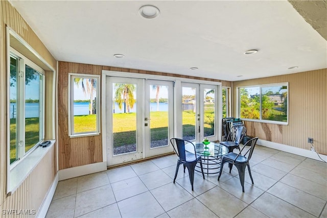 sunroom featuring a water view, french doors, and a wealth of natural light